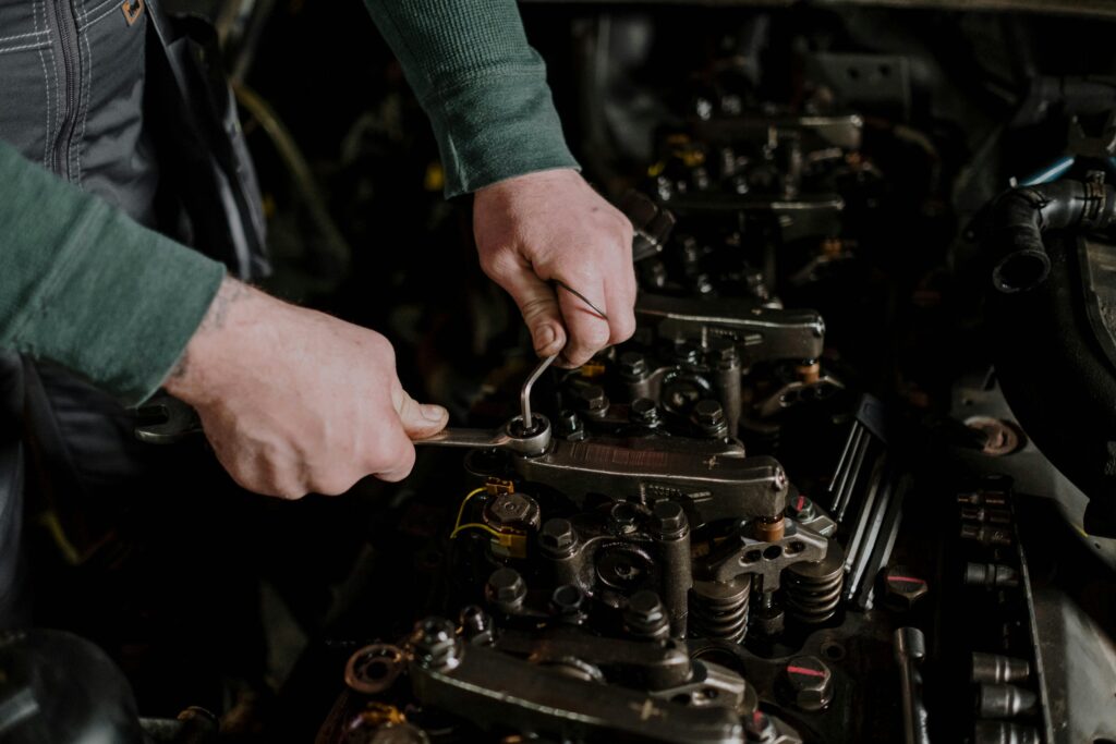 pexels-photo-7564871-7564871 Close-up of a mechanic using hand tools to fix an engine, showcasing precision and skill.